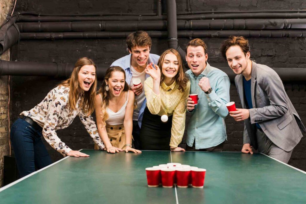 Přátelé na party hrající Beer Pong.
